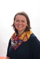 A cheerful customer smiling while wearing a lightweight scarf in a bustling city setting.