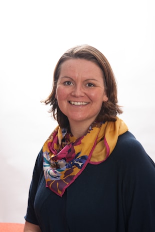 A smiling customer wearing a colorful embroidered scrunchie in natural light.