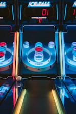 A skee-ball arcade game with illuminated targets displaying various point values, including 1,000, 2,000, 3,000, and 4,000. The colors are vibrant, with blue, red, and yellow neon lights surrounding the game. The digital scoreboard at the top reads a score of zero.