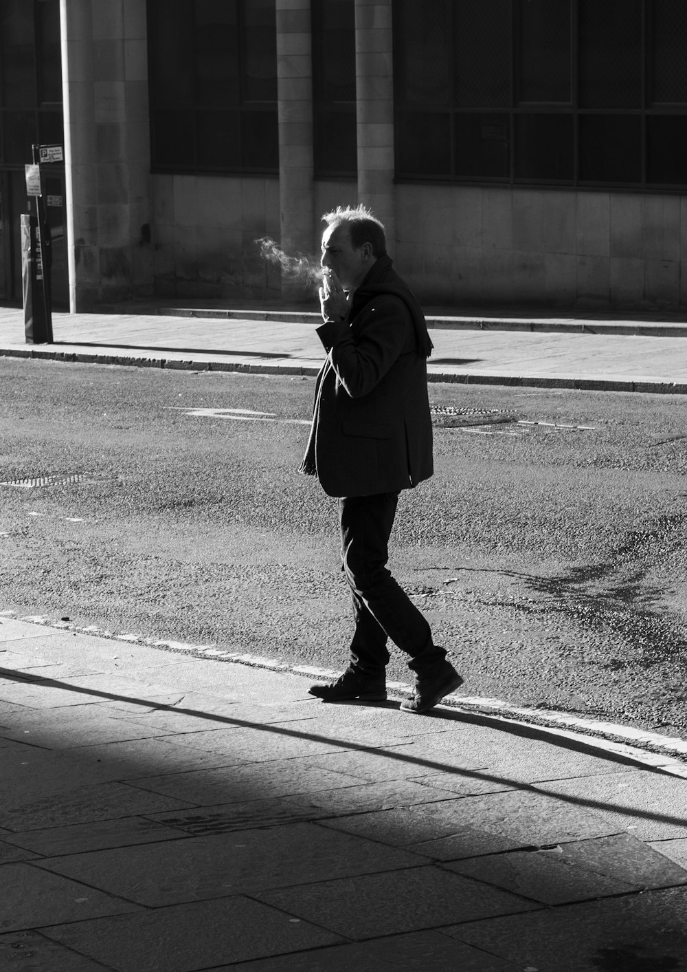 man walking while smoking on street