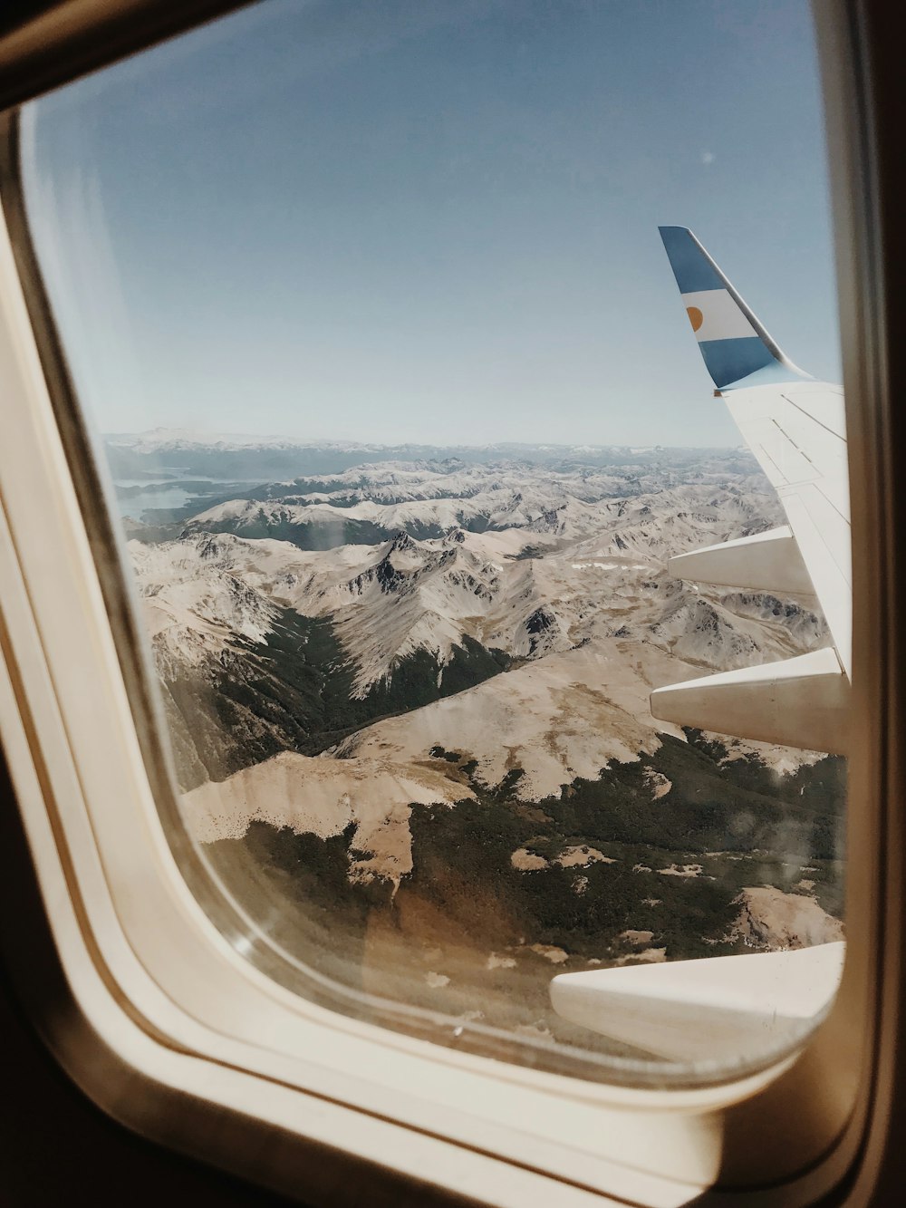 person taking picture of mountains inside airplane