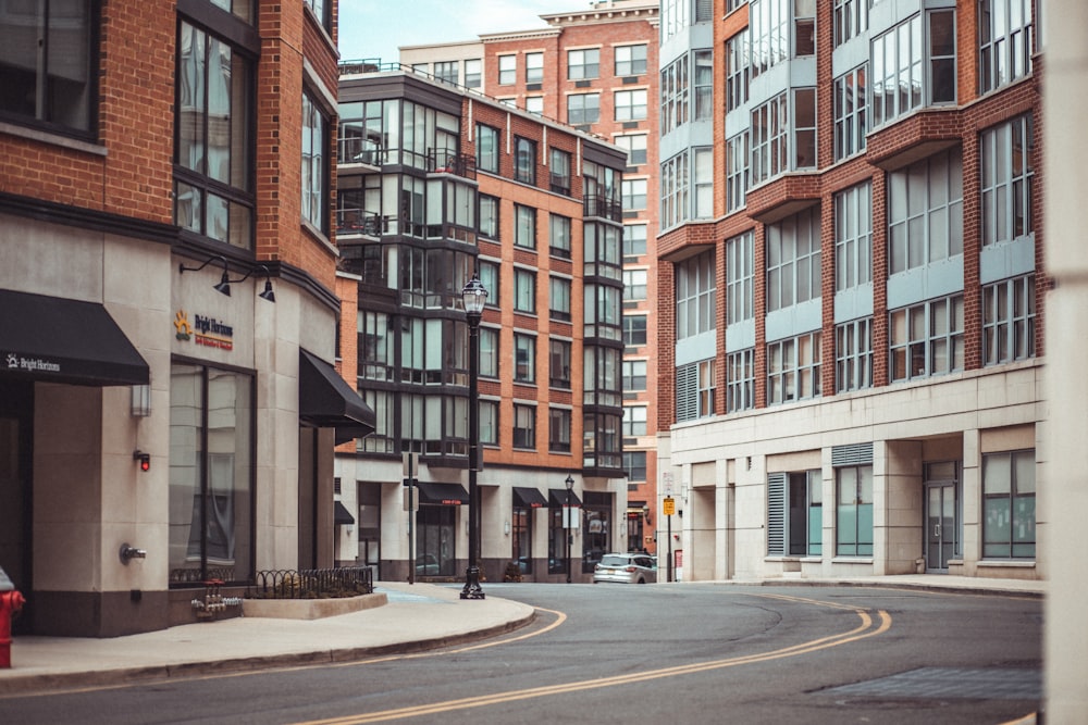 low-angle photography of road between brown-and-white concrete mid-rise buildings