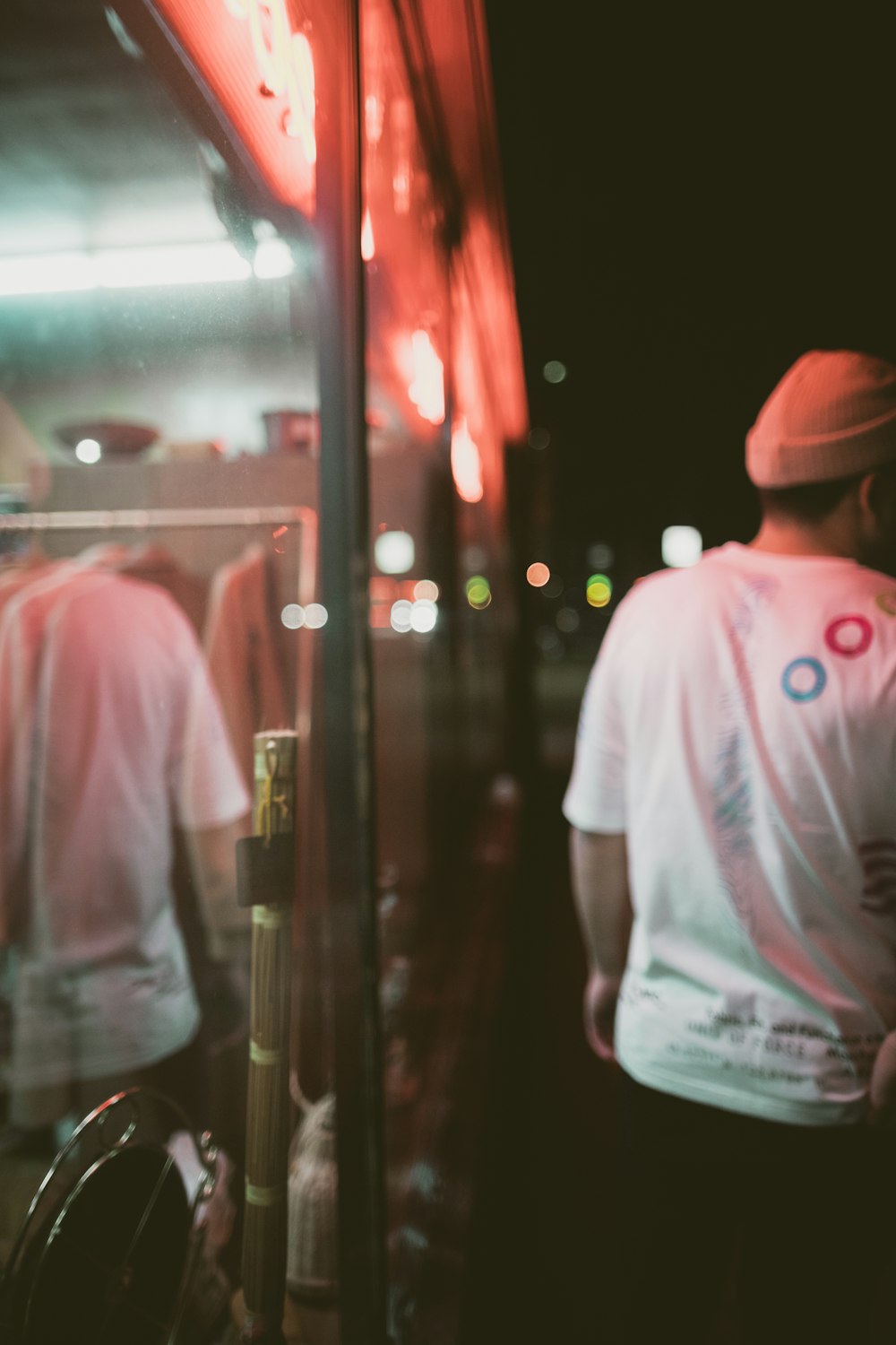 man in white, red, and blue shirt standing beside glass window