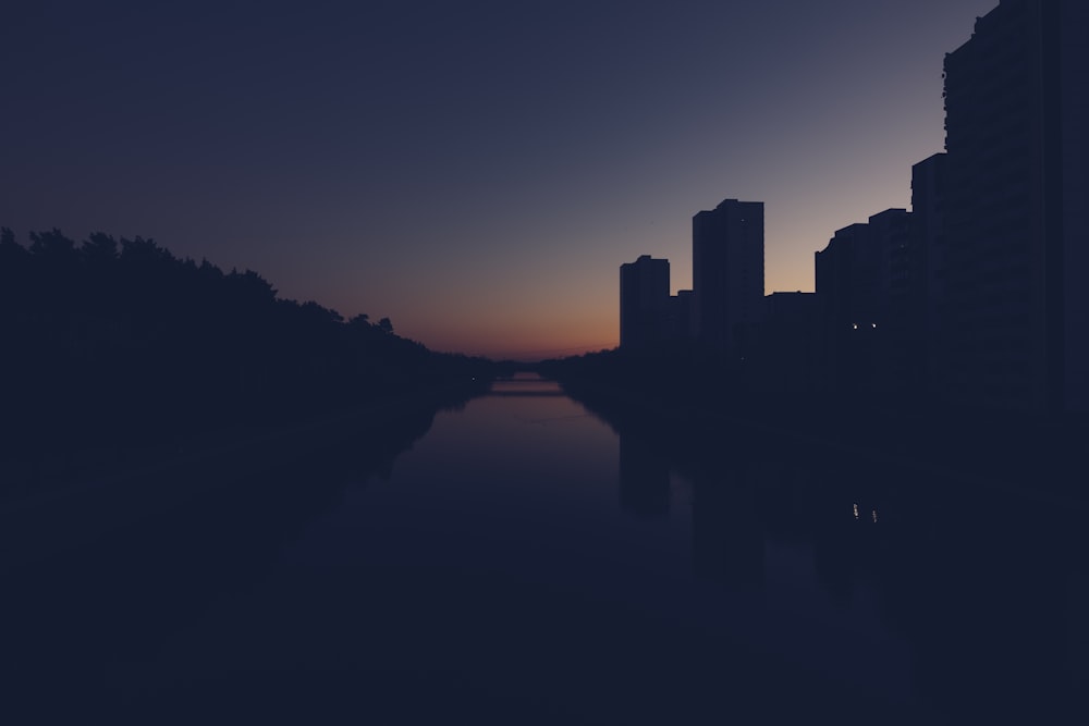 silhouette of bridge near building during golden hour