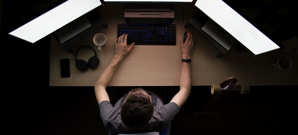 man facing three computer monitors while sitting