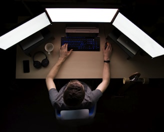 man facing three computer monitors while sitting