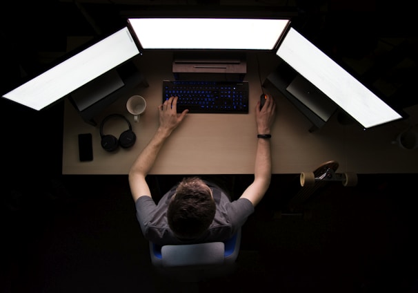 man facing three computer monitors while sitting