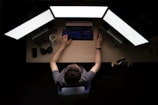man facing three computer monitors while sitting