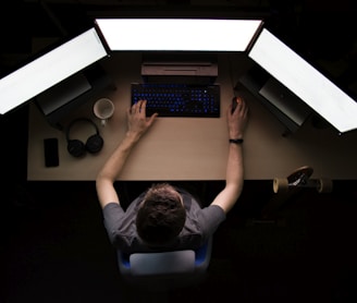 man facing three computer monitors while sitting