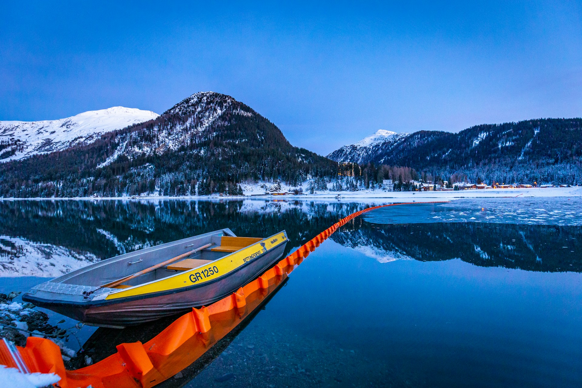 brown and yellow row boat near mountain hill under blue sky