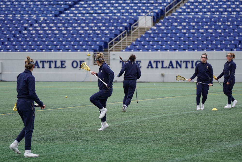 women playing lacrosse on green field during daytime