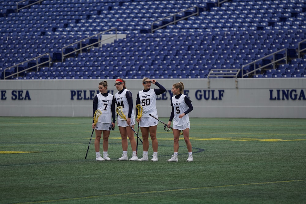 four women holding lacrosse sticks on field during daytime