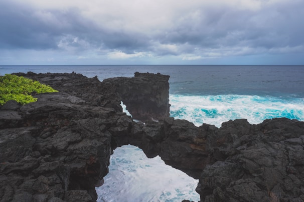 Picture of a rugged volcanic rock coastline contrasting with blue sea waves