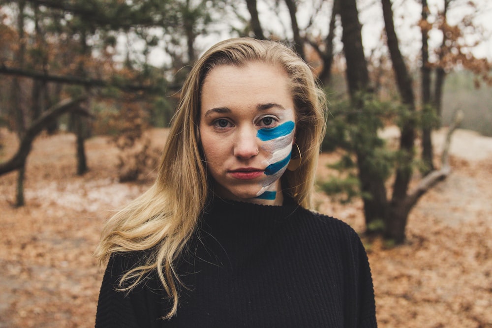 woman in black sweater with paint on her left cheek