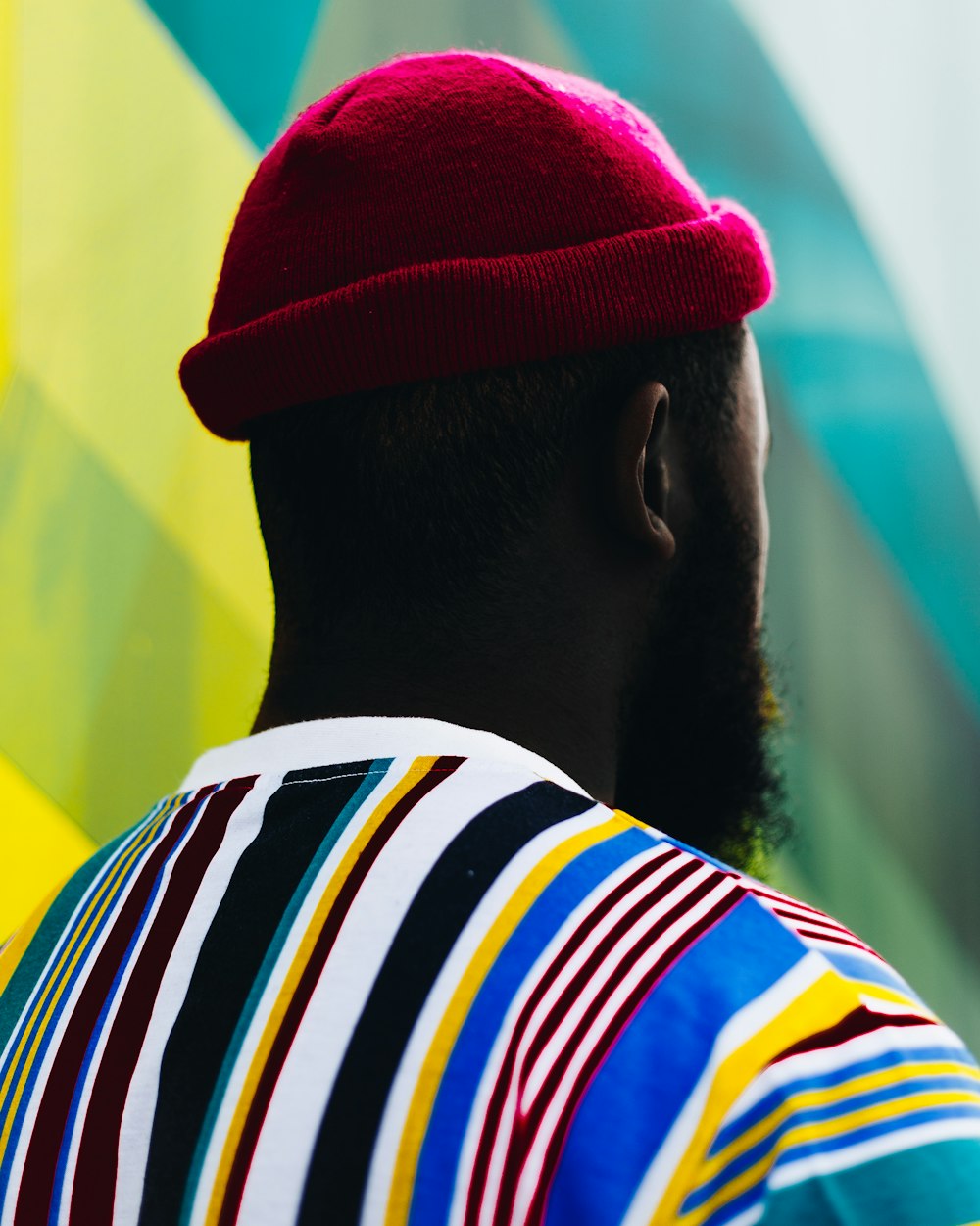 hombre con sombrero rojo y camisa multicolor mirando hacia atrás