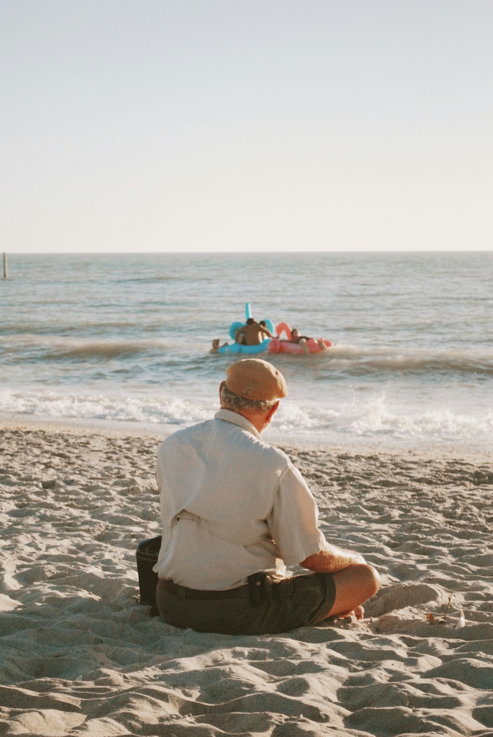 man sitting on seashore during daytime
