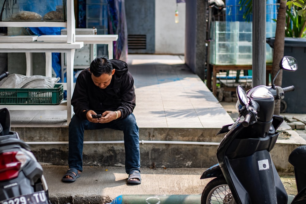 man sitting on pavement near motorcycles