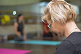 Soft focus image of a woman breathing deeply during a Pilates session on a beige floor mat.