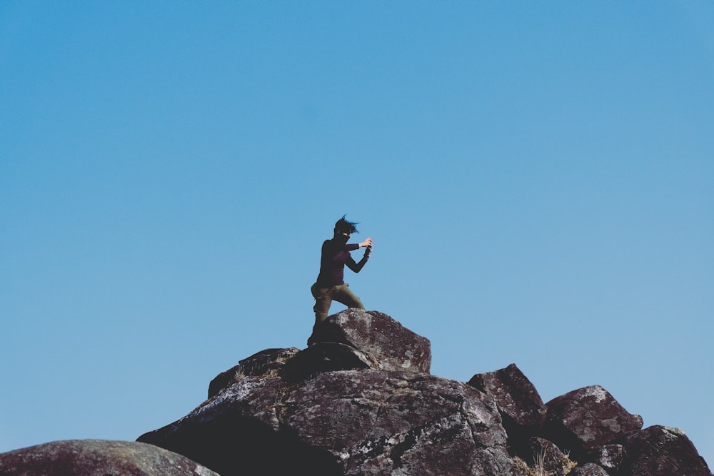 uomo in piedi sulla montagna rocciosa sotto il cielo blu