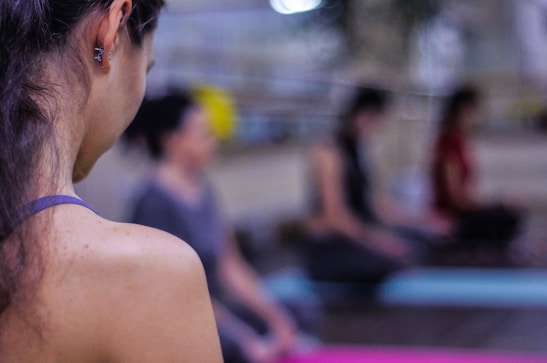 Close-up of a smiling yoga instructor demonstrating a pose to the class.
