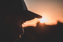 A person wearing an Aussie kangaroo cap against a sunny outback backdrop.