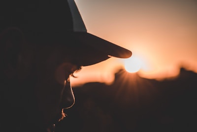 A person wearing an Aussie kangaroo cap against a sunny outback backdrop.