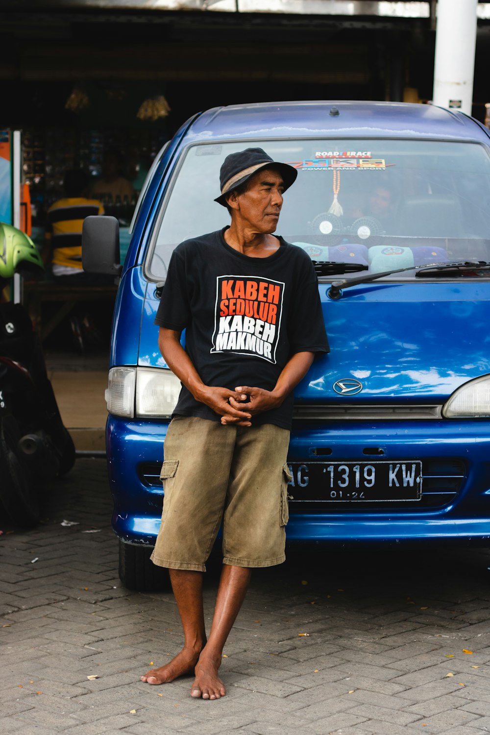 man leaning on blue vehicle during daytime