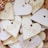 A collection of heart-shaped ceramic tags with words like 'LOVE' and different textures, arranged in a wicker basket. The hearts have small holes near the top, possibly for hanging.