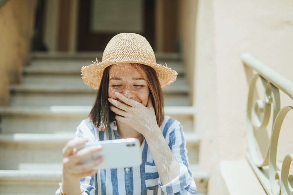 woman smiling while holding iPhone on stairs