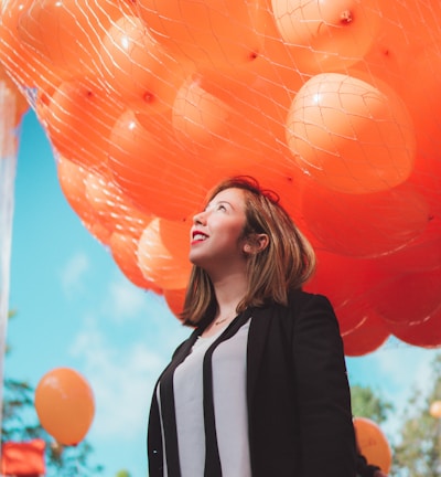smiling woman under orange balloons during daytime