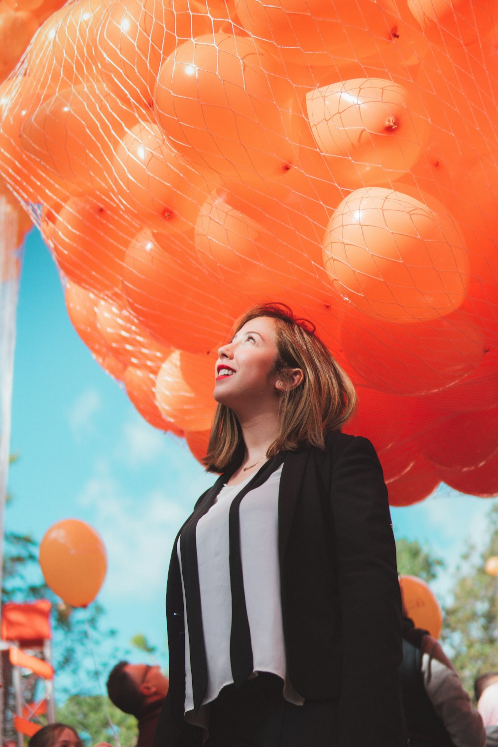 smiling woman under orange balloons during daytime