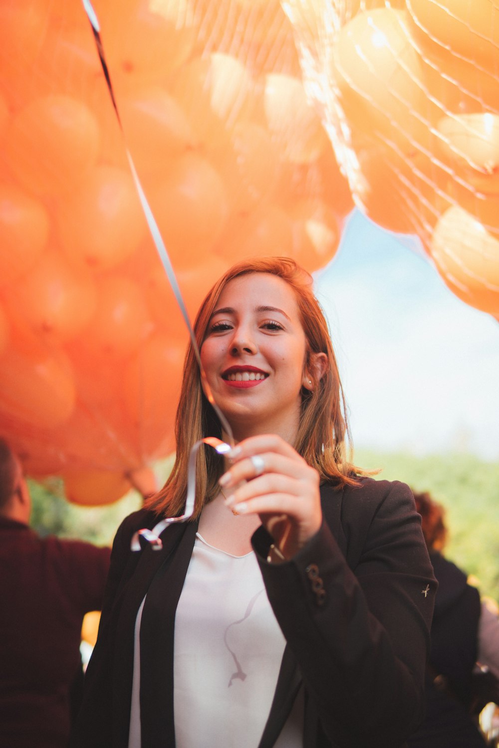 Frau steht unter orangefarbenen Luftballons