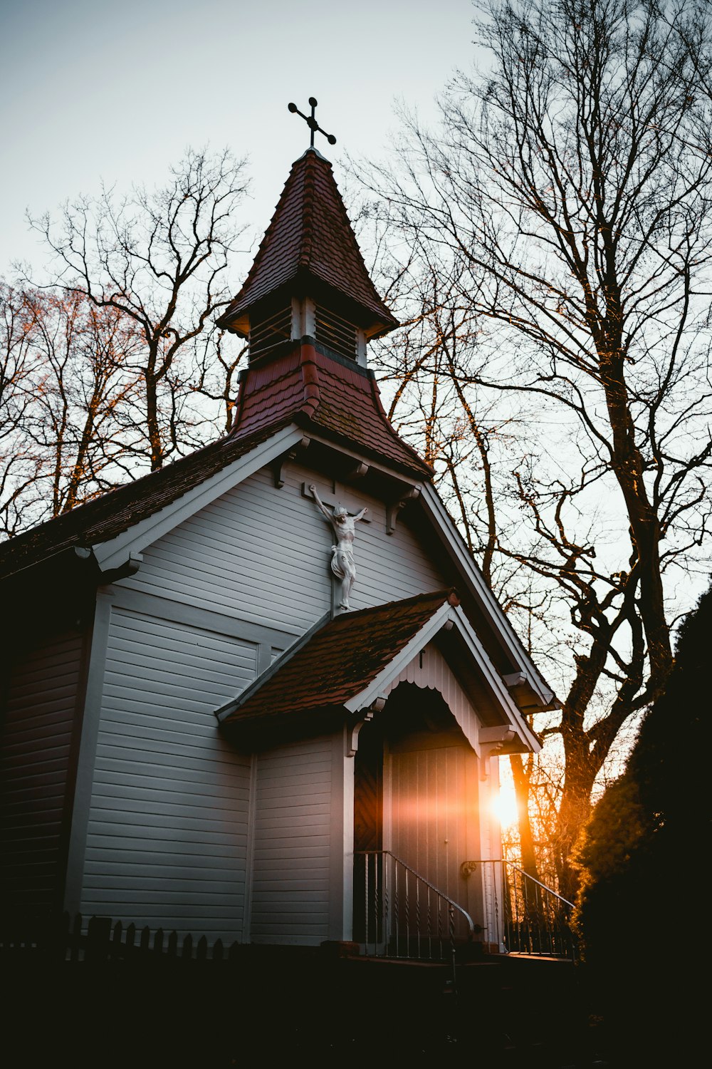 white and red painted cathedral near bare trees during golden hour