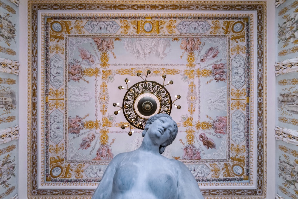 a statue of a person in front of a ceiling