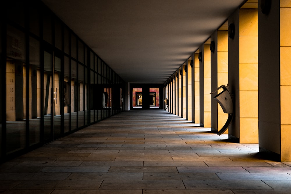 a long hallway with yellow walls and black columns