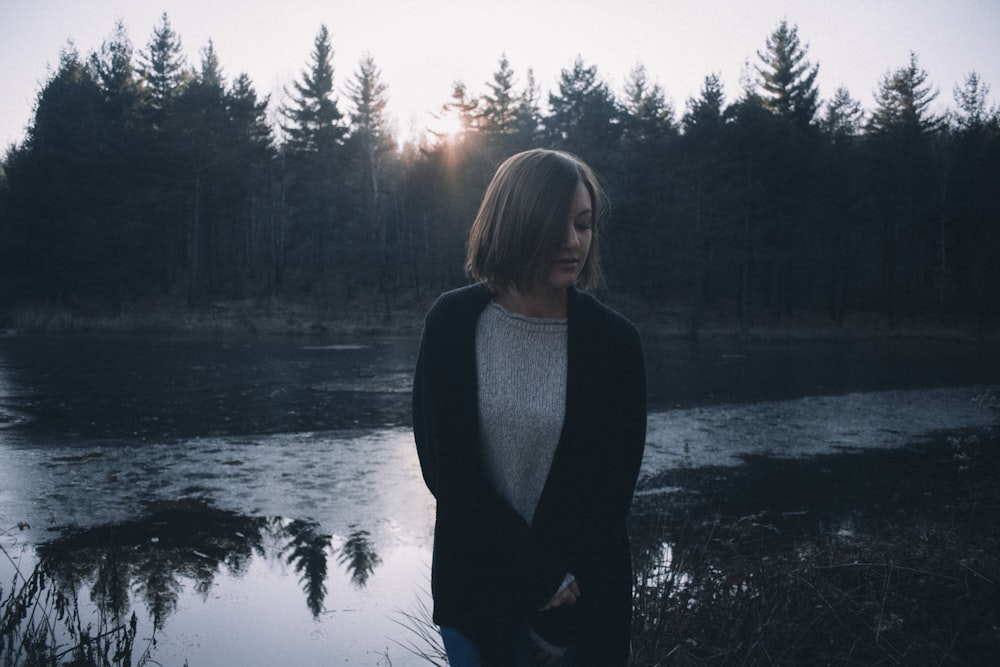 woman in black cardigan standing by the lake