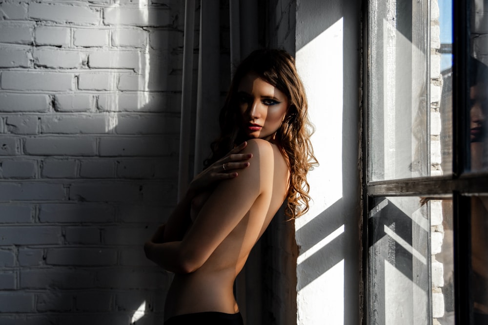 woman in black bottoms standing near white painted wall