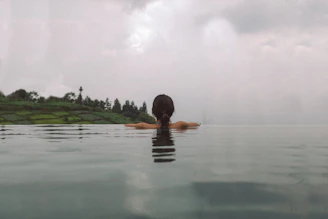 A traveler relaxing by a minimalist hotel pool overlooking lush green rice terraces.