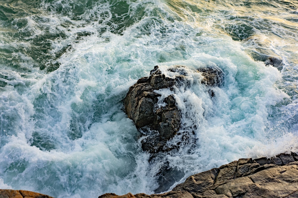 Fotografía de gran angular de olas sobre piedra gris