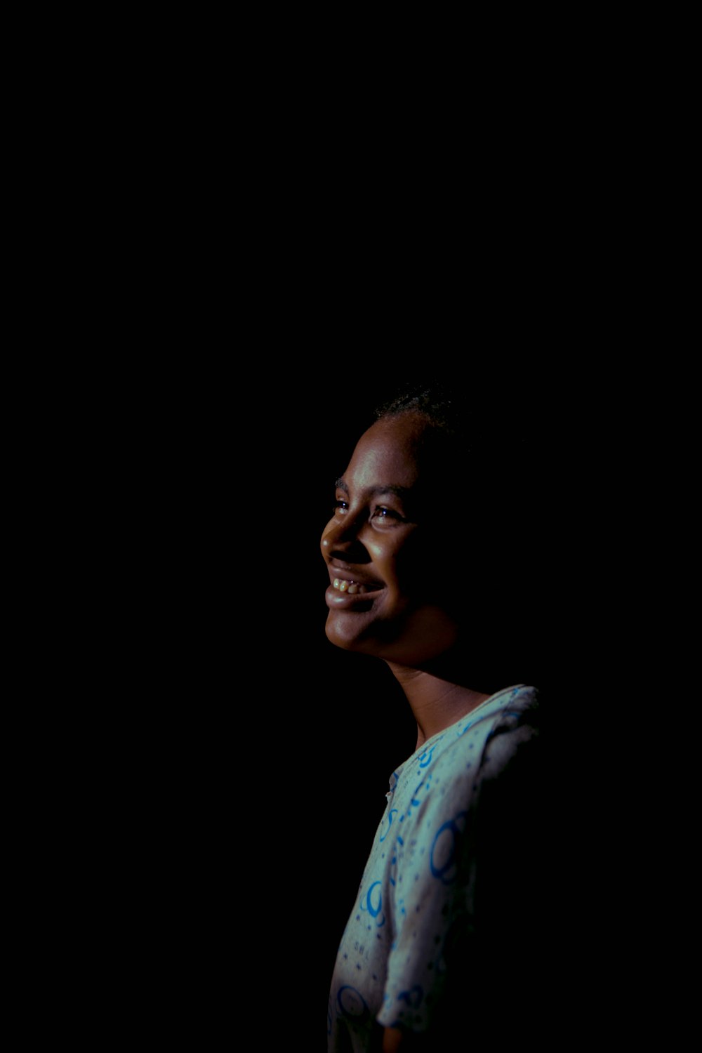 a woman standing in the dark with a smile on her face