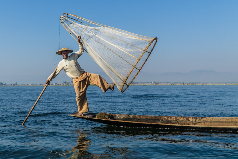 hombre sosteniendo palo y red de pesca en forma de cono
