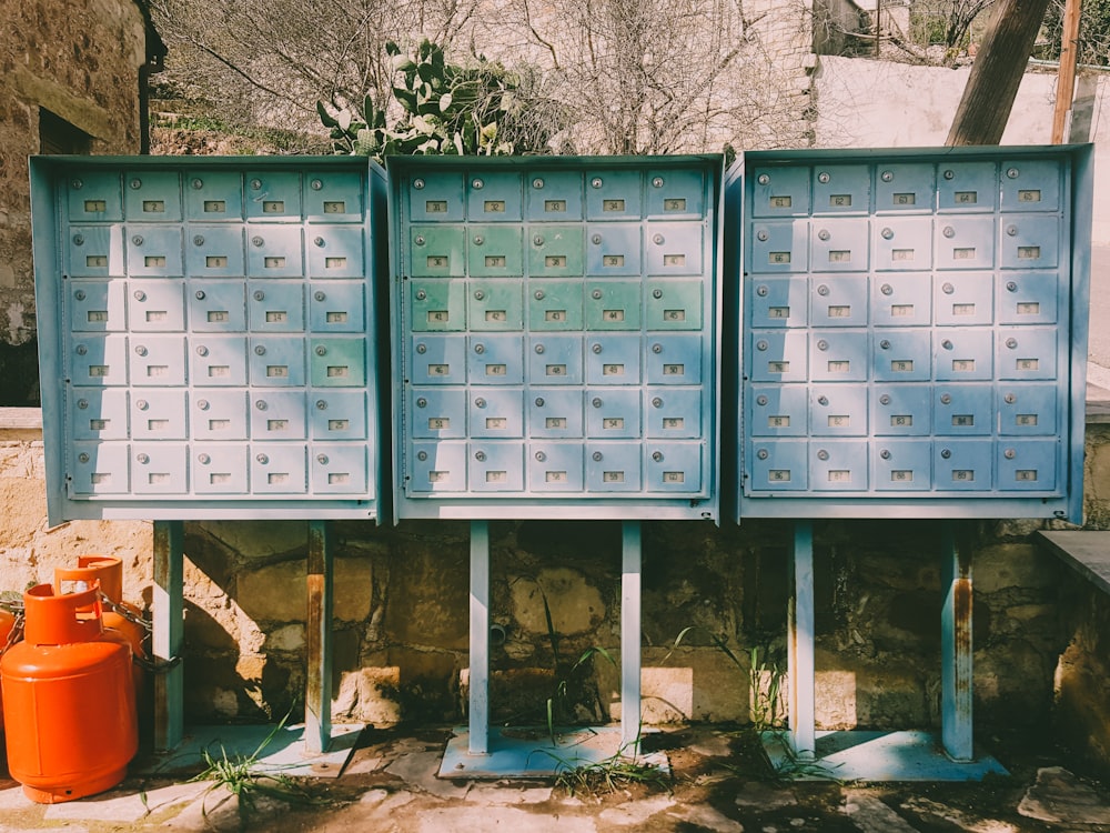 two orange propane tanks place beside three metal mailboxes