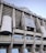 Tall structural facade of a large stadium with visible columns and a silver-gray exterior. The signage reads 'Estadio Santiago Bernabéu' and there is a prominent logo of Real Madrid Club de Fútbol displayed.