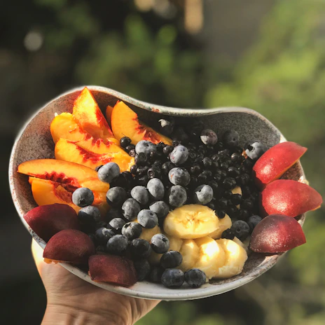 Close-up of hands holding a variety of colorful fresh fruits in a natural setting.