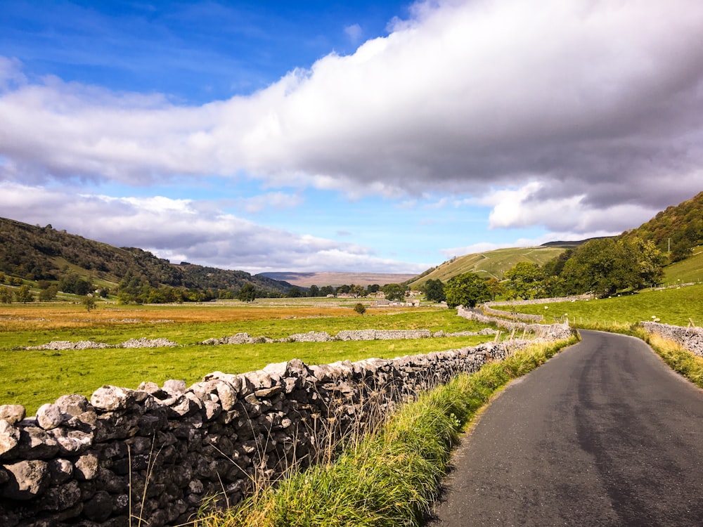 empty road in between green fields at daytime