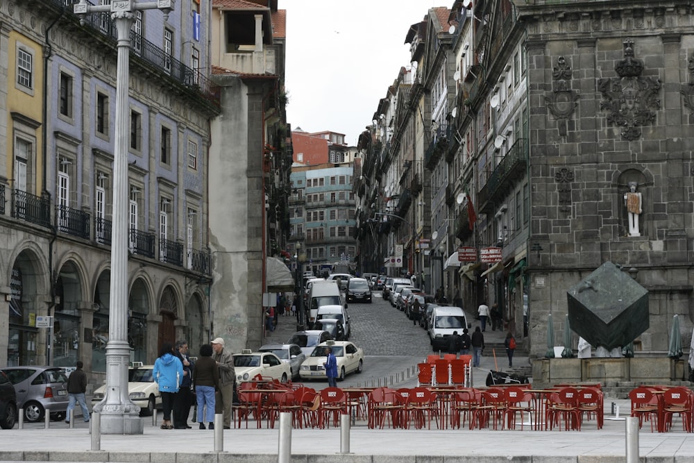 people walking on pathway near buildings and different vehicles on road during daytime