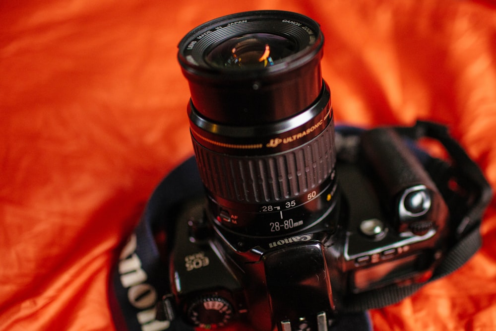 black Nikon DSLR camera on orange textile
