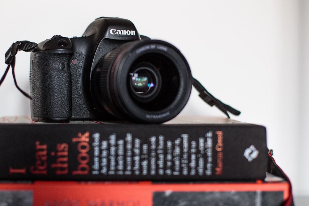 black Canon DSLR camera on top of black book