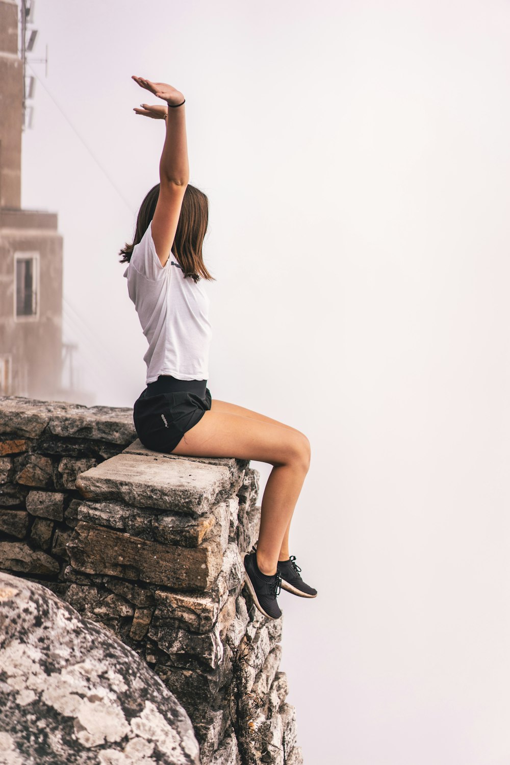 woman sitting on edge while raising hand