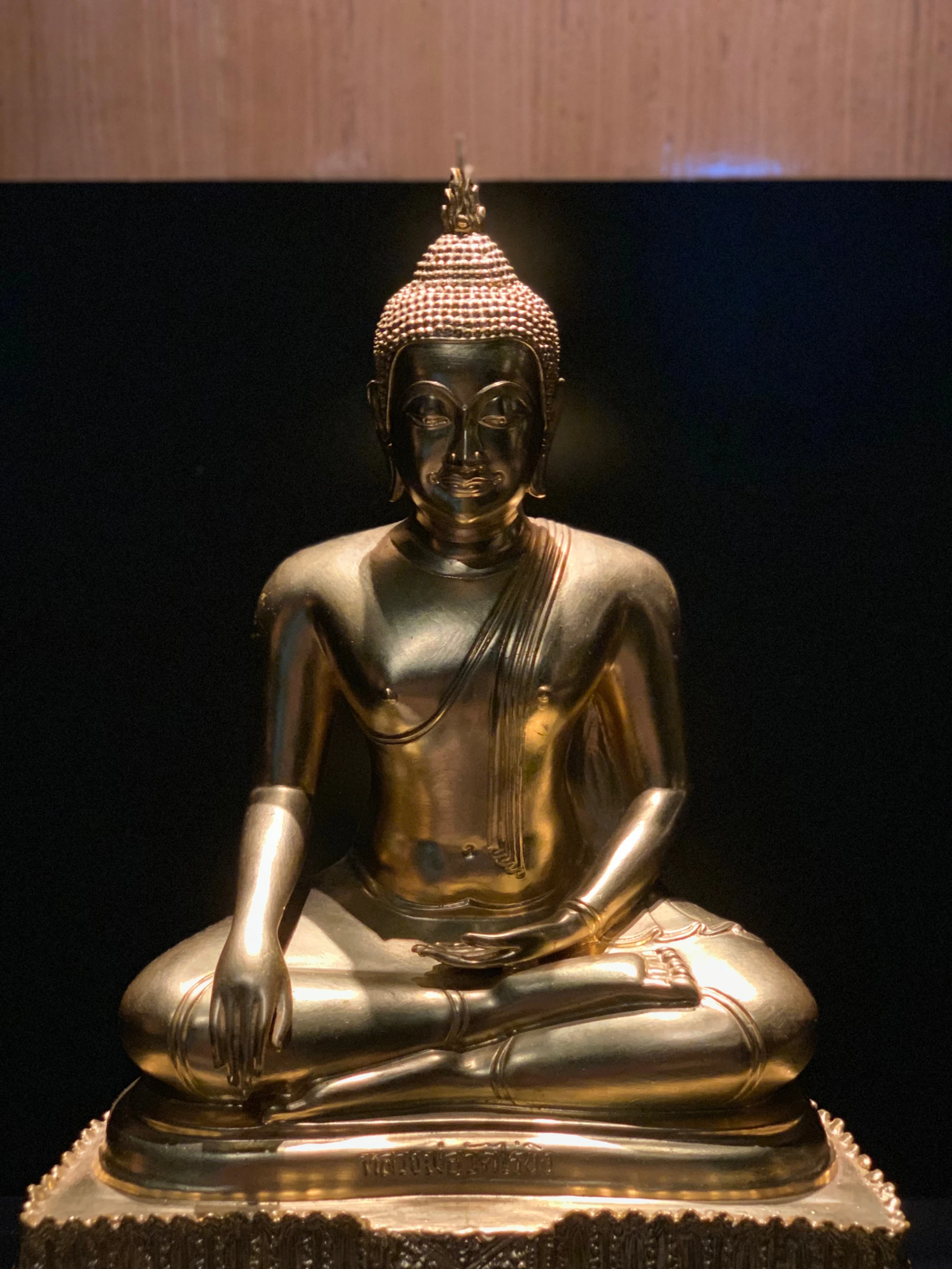 A serene golden Buddha statue seated gracefully against a soft white background, bathed in gentle light that highlights intricate details.